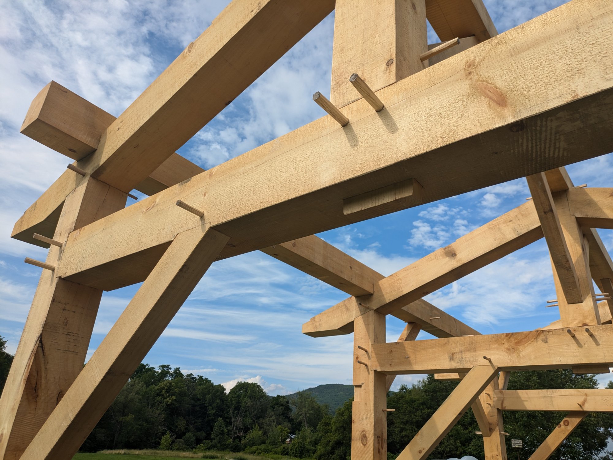 Timber frame joinery with wooden pegs against blue sky